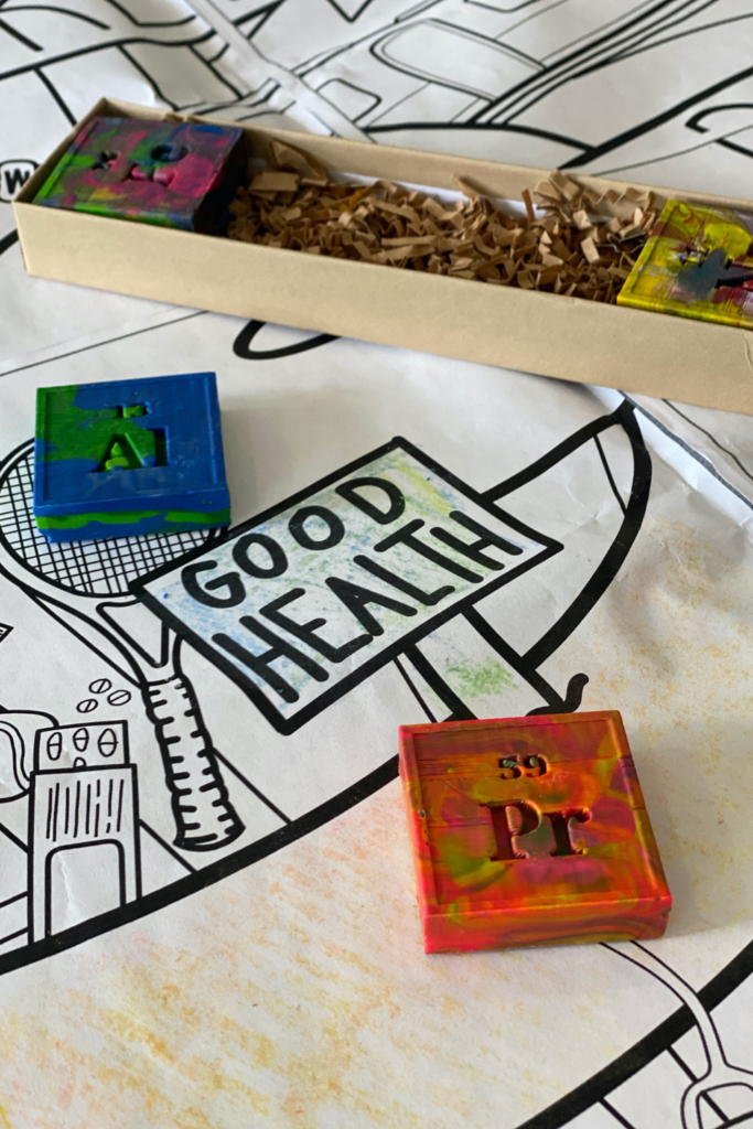 "good health" coloring page displayed on table top with periodic table of elements crayons