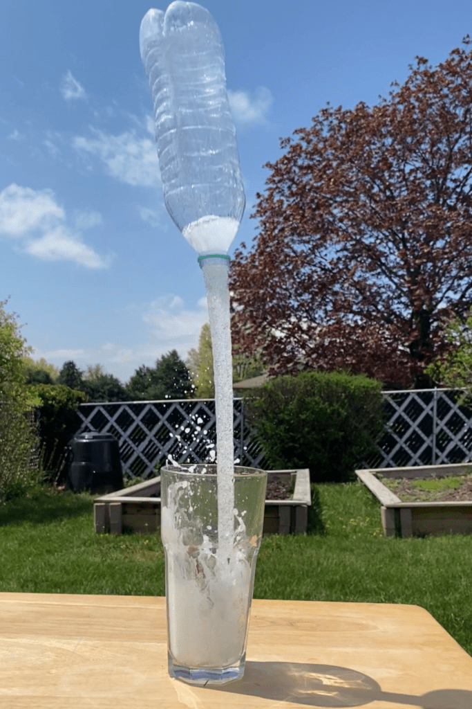 Upside down plastic water bottle propelled out of glass jar due to chemical reaction of Alka-Seltzer and water.