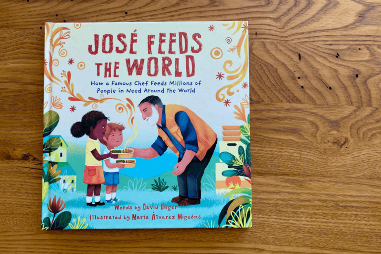 The book “Jose Feeds the World” sits on top of a wooden table.